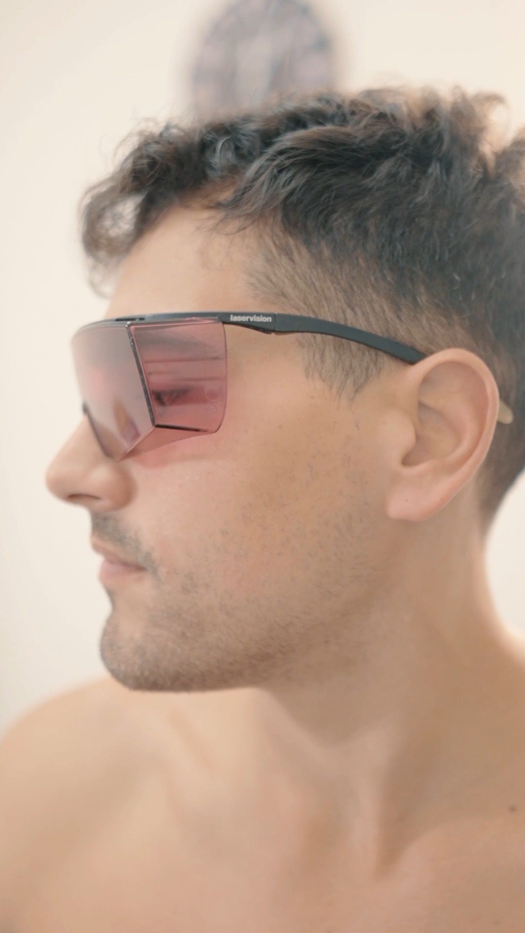Uomo con gli occhiali protettivi si tocca il viso dopo la seduta di epilazione laser
