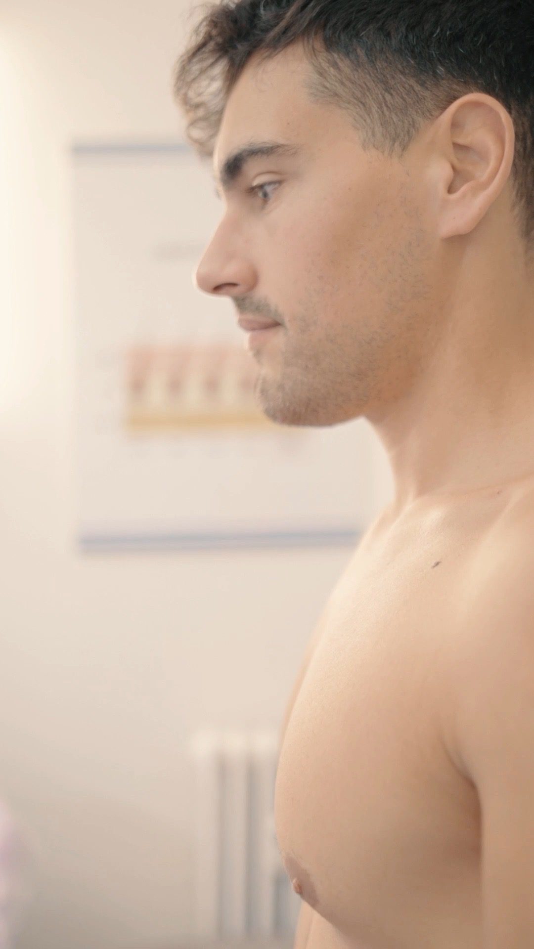 Uomo a torso nudo di profilo nello studio Lazer Shine prima della seduta
